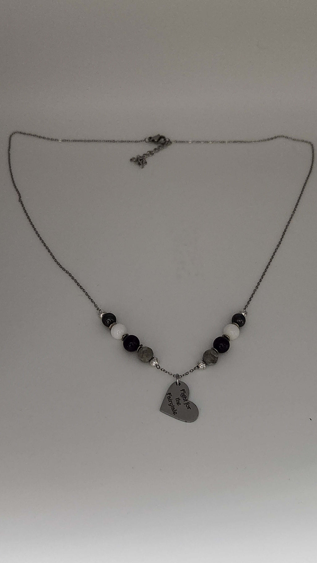 Celebrate identity with this demisexual pride necklace. Silver-plated, nickel-free stainless steel with a heart pendant engraved “Fight for the Fairytale.” Adjustable 18–20 inches.