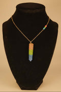 Celebrate polysexual pride with a handcrafted resin pendant filled with rhodonite, peridot, and lapis gemstone sand. On Gold plated chain.