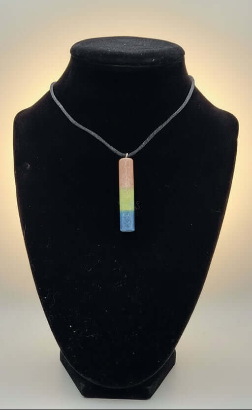 Celebrate polysexual pride with a handcrafted resin pendant filled with rhodonite, peridot, and lapis gemstone sand. On Nylon cord.