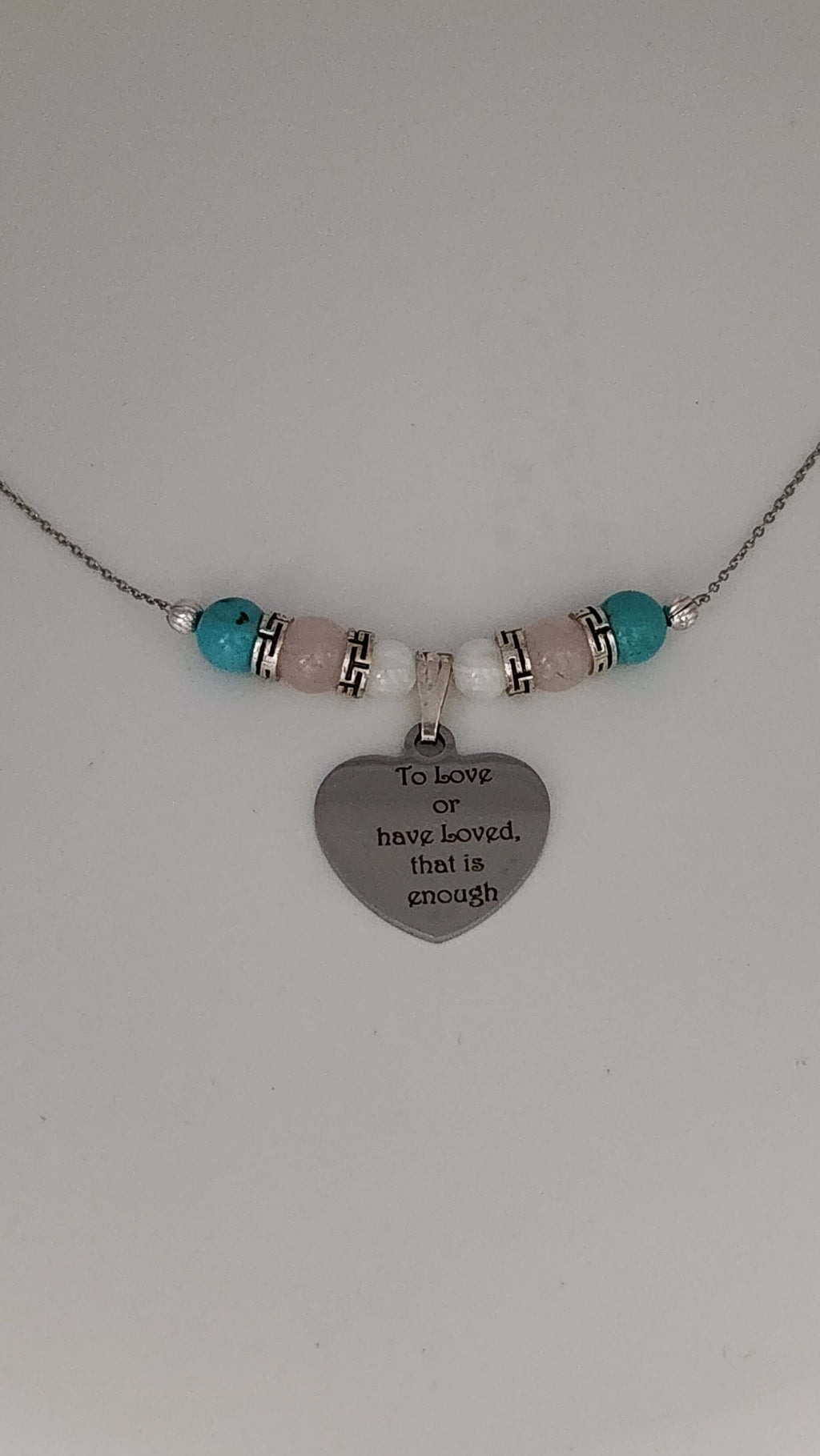 Premium transgender pride necklace featuring blue magnesite, rose quartz, and mother of pearl. Nickel-free, plastic-free, silver-plated stainless steel with engraved heart pendant.